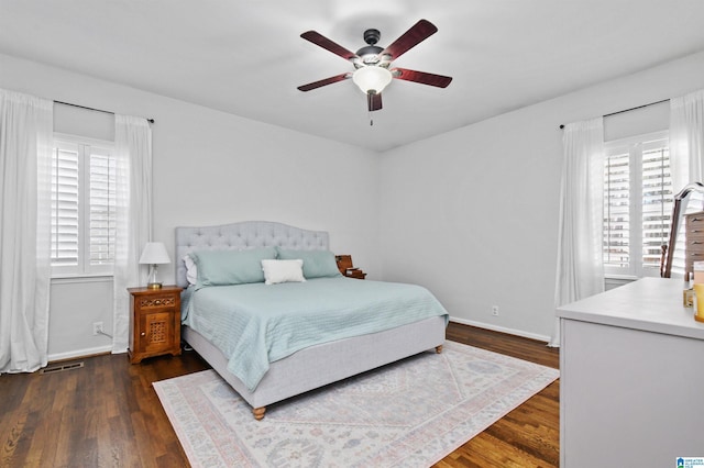 bedroom featuring ceiling fan, dark hardwood / wood-style floors, and multiple windows