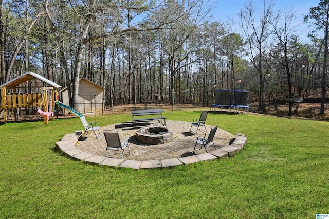 view of yard with a storage shed, a patio area, a trampoline, a playground, and a fire pit