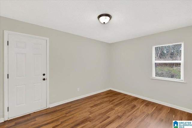 empty room featuring wood-type flooring and a textured ceiling