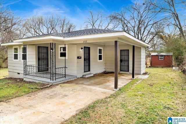 view of front of home with a carport, a storage unit, and a front lawn