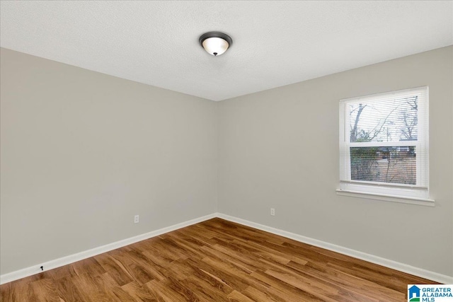 unfurnished room with wood-type flooring and a textured ceiling