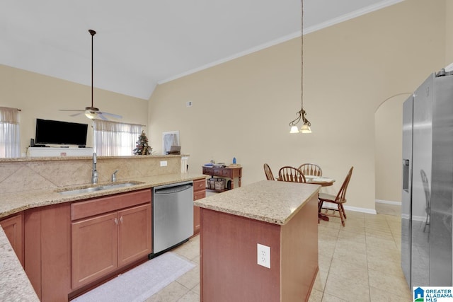 kitchen featuring sink, hanging light fixtures, appliances with stainless steel finishes, a kitchen island, and light stone countertops