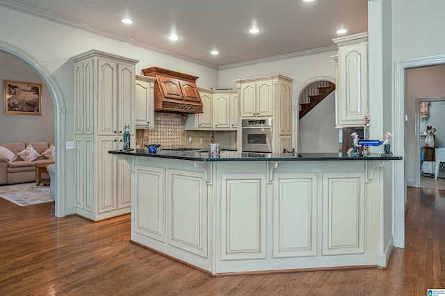 kitchen with wood-type flooring, appliances with stainless steel finishes, cream cabinets, and kitchen peninsula