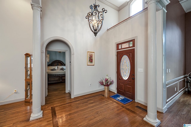 foyer featuring decorative columns and dark wood-type flooring