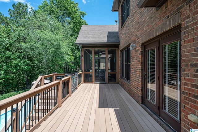 wooden deck featuring a sunroom and a swimming pool