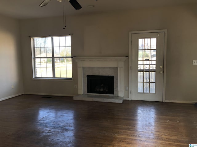 unfurnished living room with dark wood-type flooring, a wealth of natural light, and ceiling fan