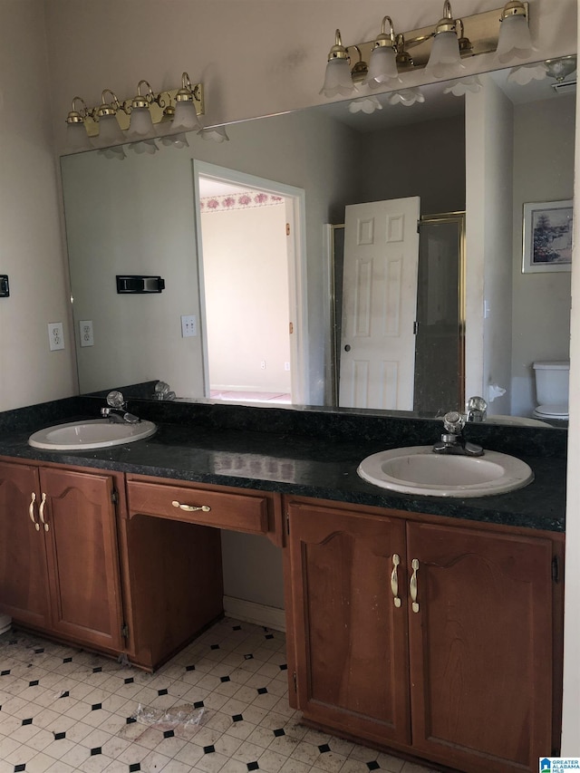 bathroom with vanity, toilet, and a shower with door