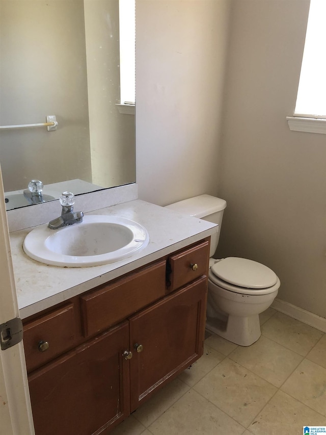 bathroom featuring vanity, plenty of natural light, tile patterned floors, and toilet