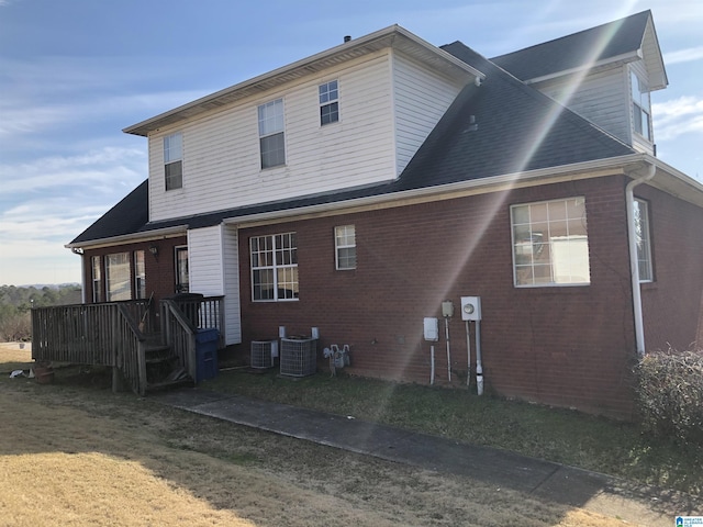 rear view of property with a porch, a lawn, and central air condition unit