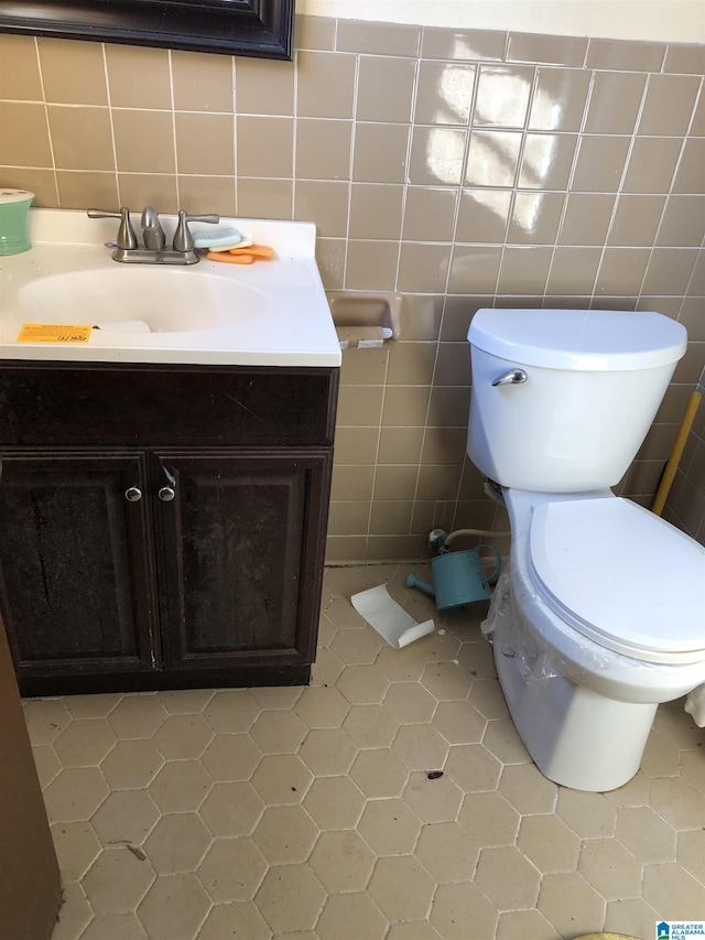 bathroom with vanity, toilet, and tile walls