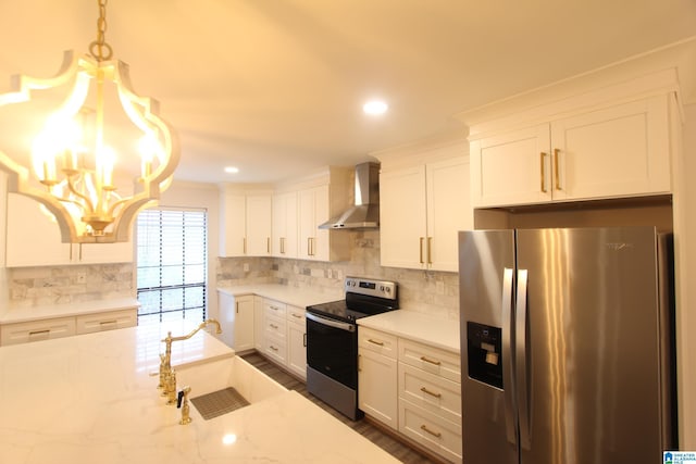 kitchen with appliances with stainless steel finishes, decorative light fixtures, white cabinetry, light stone counters, and wall chimney exhaust hood