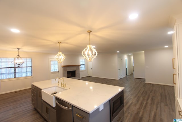 kitchen featuring hanging light fixtures, appliances with stainless steel finishes, a kitchen island with sink, and sink