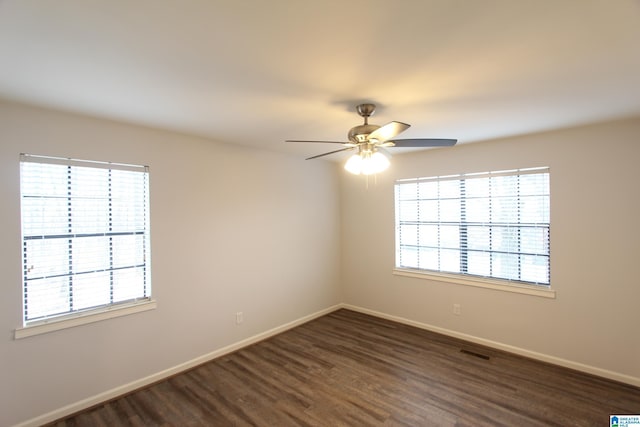 unfurnished room with a wealth of natural light, dark hardwood / wood-style floors, and ceiling fan