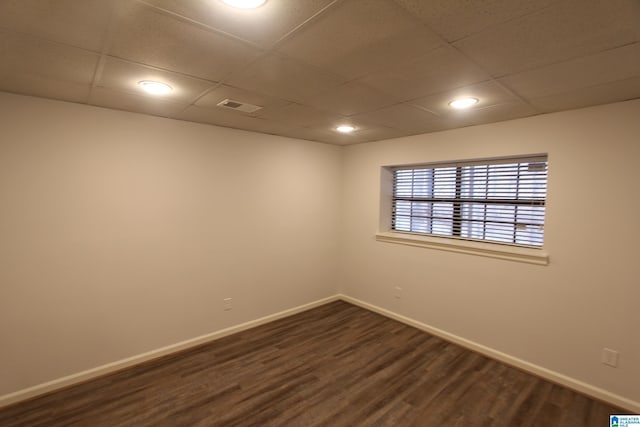 empty room featuring dark hardwood / wood-style flooring and a paneled ceiling