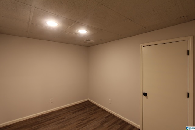 spare room with dark hardwood / wood-style floors and a drop ceiling