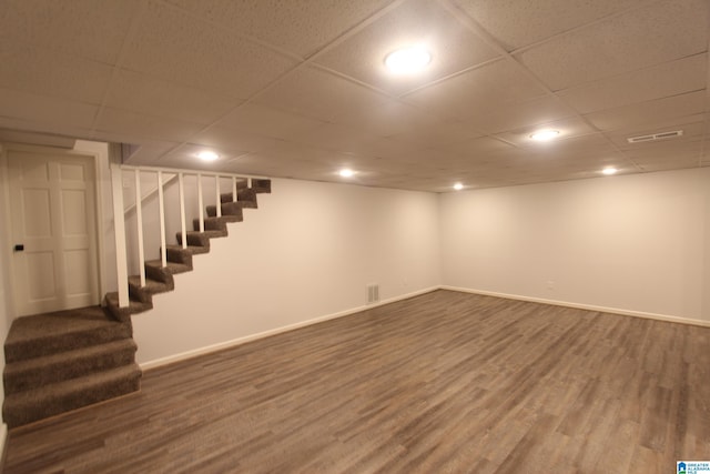 basement featuring dark wood-type flooring and a paneled ceiling