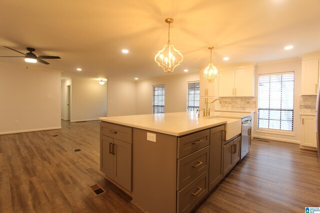 kitchen with dark wood-type flooring, white cabinetry, hanging light fixtures, decorative backsplash, and stainless steel dishwasher