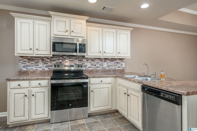 kitchen featuring visible vents, appliances with stainless steel finishes, cream cabinets, and a sink