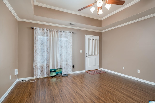 empty room with visible vents, a raised ceiling, and wood finished floors