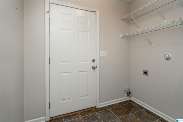 laundry area with laundry area, dark tile patterned flooring, baseboards, and electric dryer hookup