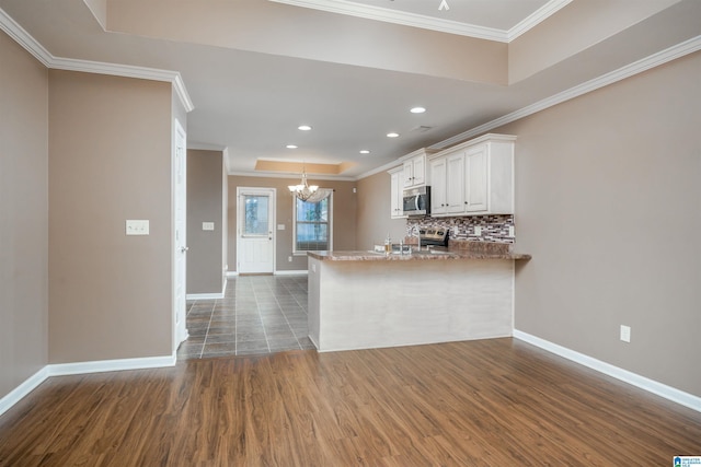 kitchen featuring a raised ceiling, crown molding, backsplash, and stainless steel appliances