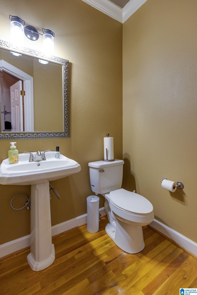 bathroom featuring toilet, ornamental molding, and wood-type flooring