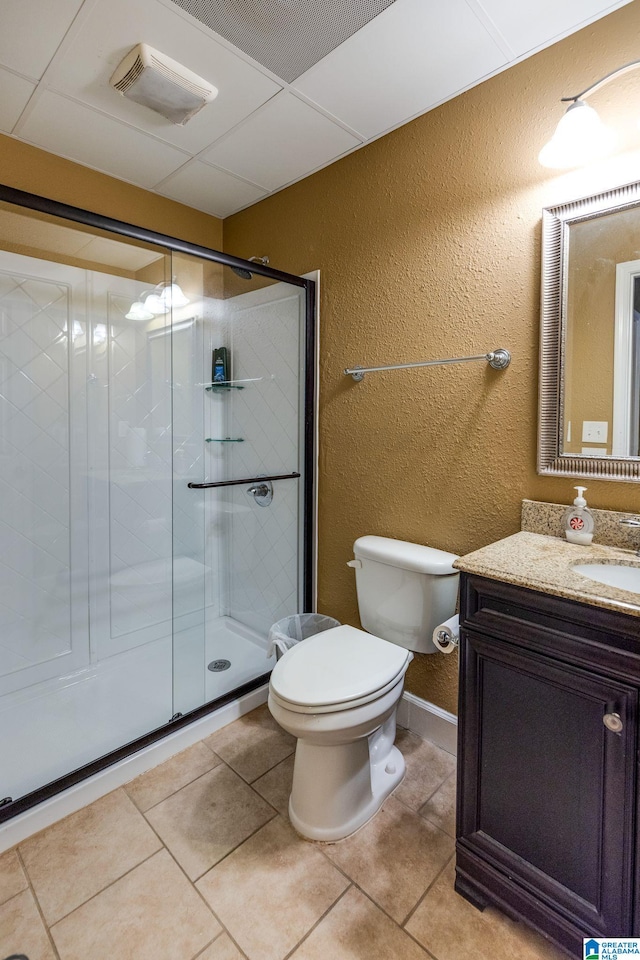 bathroom featuring tile patterned floors, toilet, vanity, and a shower with shower door