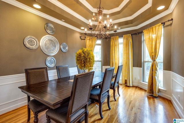 dining room with light hardwood / wood-style flooring, a chandelier, crown molding, and a raised ceiling