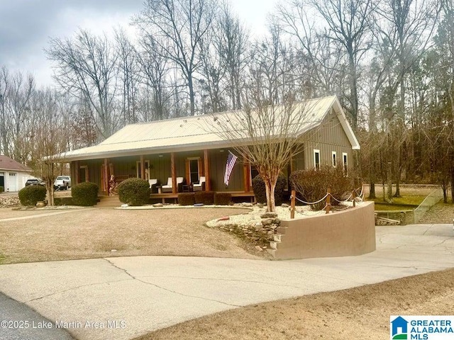 view of front of home featuring covered porch, concrete driveway, and metal roof