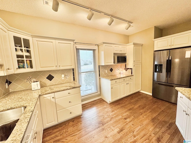 kitchen featuring light stone counters, stainless steel appliances, light hardwood / wood-style floors, and white cabinets