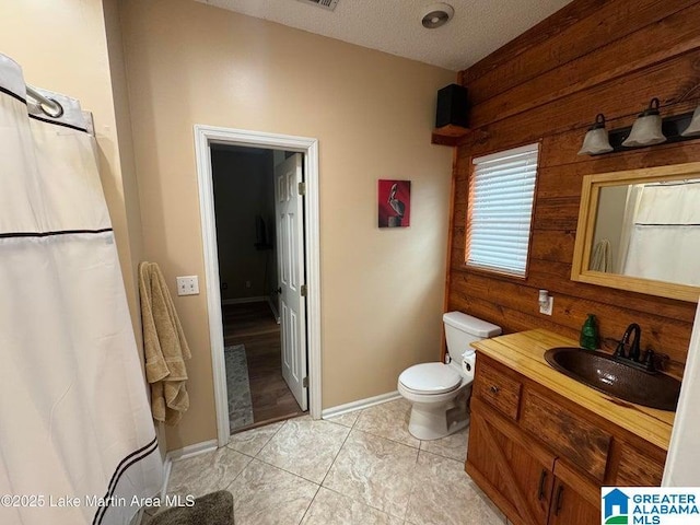 bathroom featuring toilet, a textured ceiling, vanity, wooden walls, and tile patterned flooring