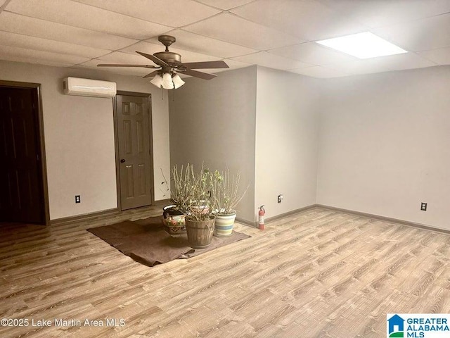 spare room featuring ceiling fan, a paneled ceiling, a wall unit AC, and light hardwood / wood-style floors