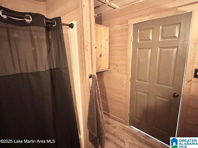 bathroom with a shower with curtain and wood walls