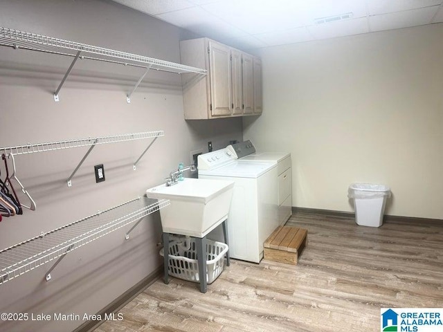 laundry room featuring cabinets, washer and clothes dryer, and light hardwood / wood-style flooring