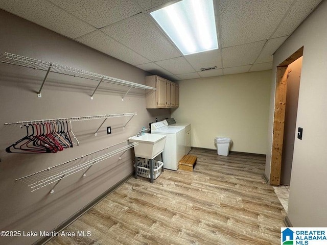 washroom with sink, cabinets, washing machine and clothes dryer, and light wood-type flooring