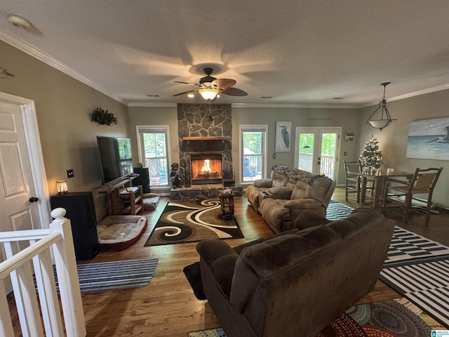 living area featuring a wealth of natural light, wood finished floors, crown molding, and ceiling fan