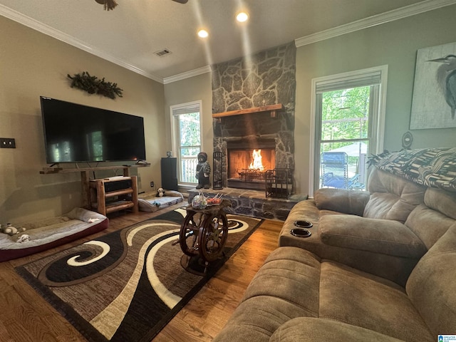 living room featuring a fireplace, visible vents, ornamental molding, and wood finished floors