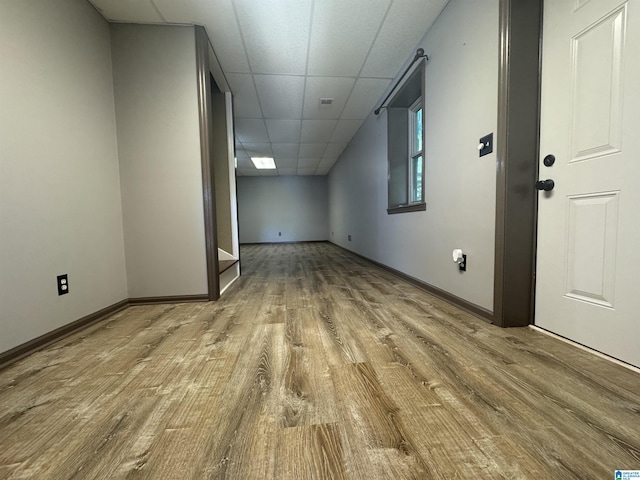 interior space featuring wood finished floors, baseboards, and a drop ceiling