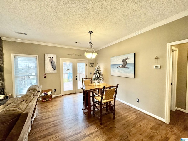 dining area featuring dark wood-type flooring, ornamental molding, french doors, and plenty of natural light