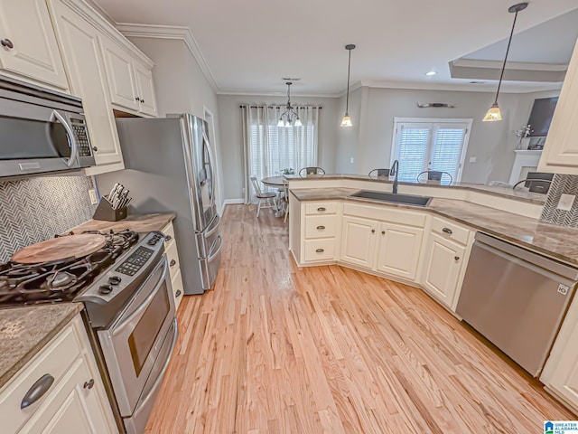 kitchen with light stone countertops, appliances with stainless steel finishes, sink, and pendant lighting