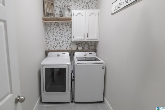 laundry area with light tile patterned floors, washer and clothes dryer, and cabinets