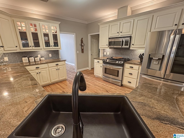 kitchen with sink, light hardwood / wood-style flooring, ornamental molding, stainless steel appliances, and decorative backsplash