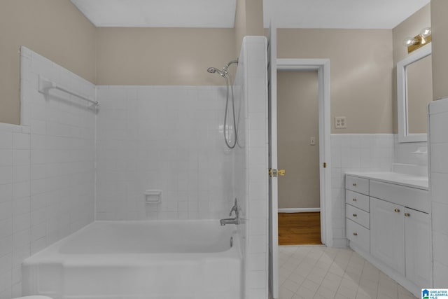 bathroom featuring vanity, tile patterned flooring, tiled shower / bath combo, and tile walls