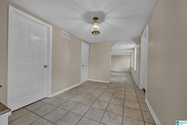 tiled empty room with a chandelier