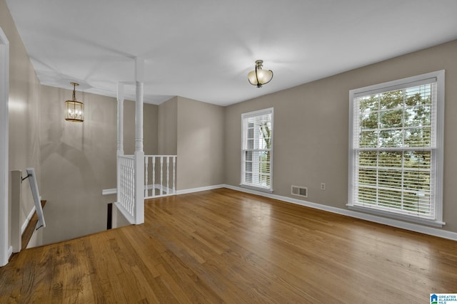 unfurnished room featuring an inviting chandelier and hardwood / wood-style flooring