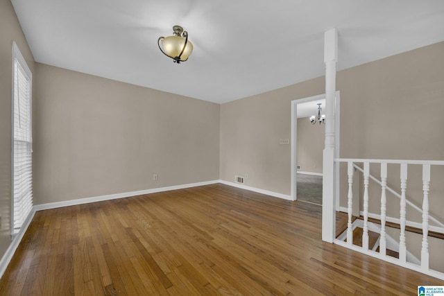 spare room featuring hardwood / wood-style floors and a notable chandelier