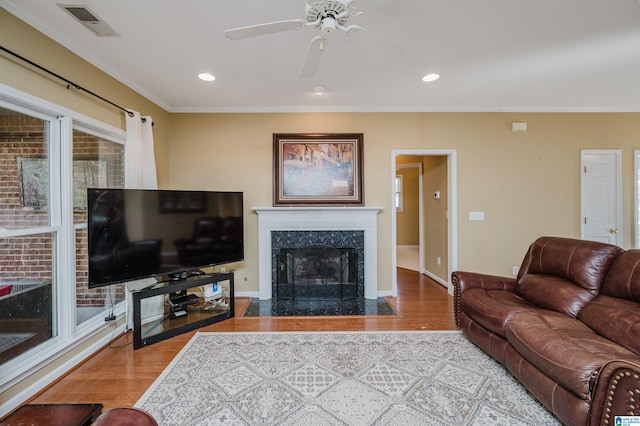 living room with hardwood / wood-style flooring, crown molding, and a fireplace