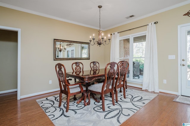 dining space with wood-type flooring, ornamental molding, and a chandelier