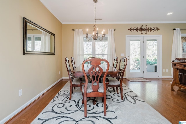 dining area with an inviting chandelier, crown molding, and wood-type flooring