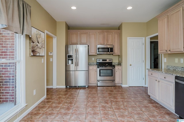 kitchen with appliances with stainless steel finishes, light tile patterned floors, and light stone counters